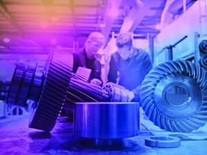 Male and female engineers assembling industrial gearbox in engineering factory